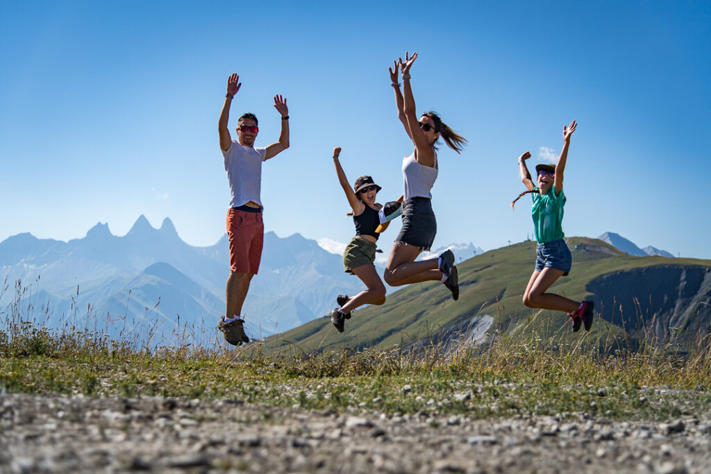 Famille sautant en randonnée à La Toussuire face aux montagnes.