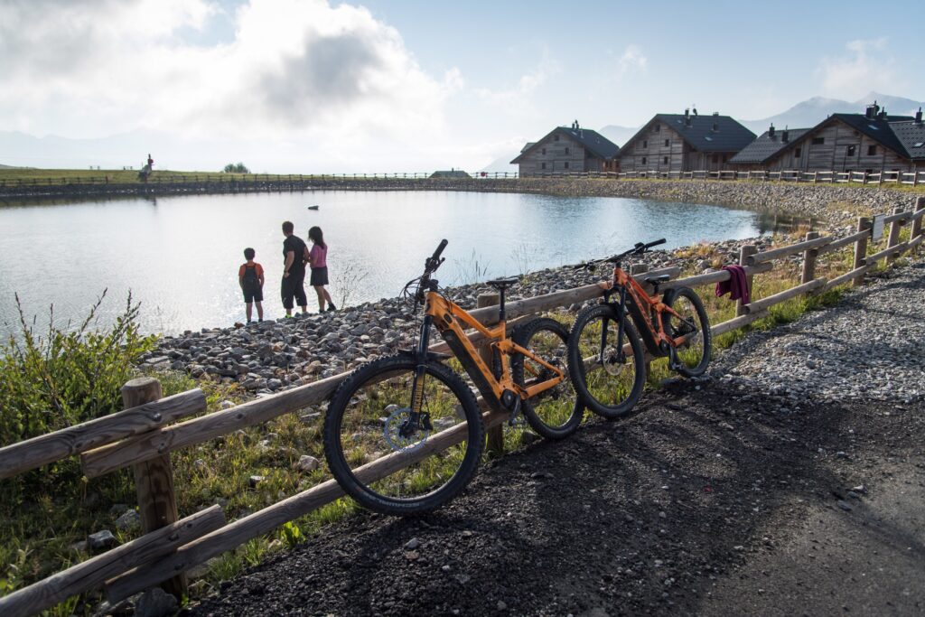 VTT Electrique poser contre une rambarde en bois devant le lac de l'Eriscal avec trois personnes.