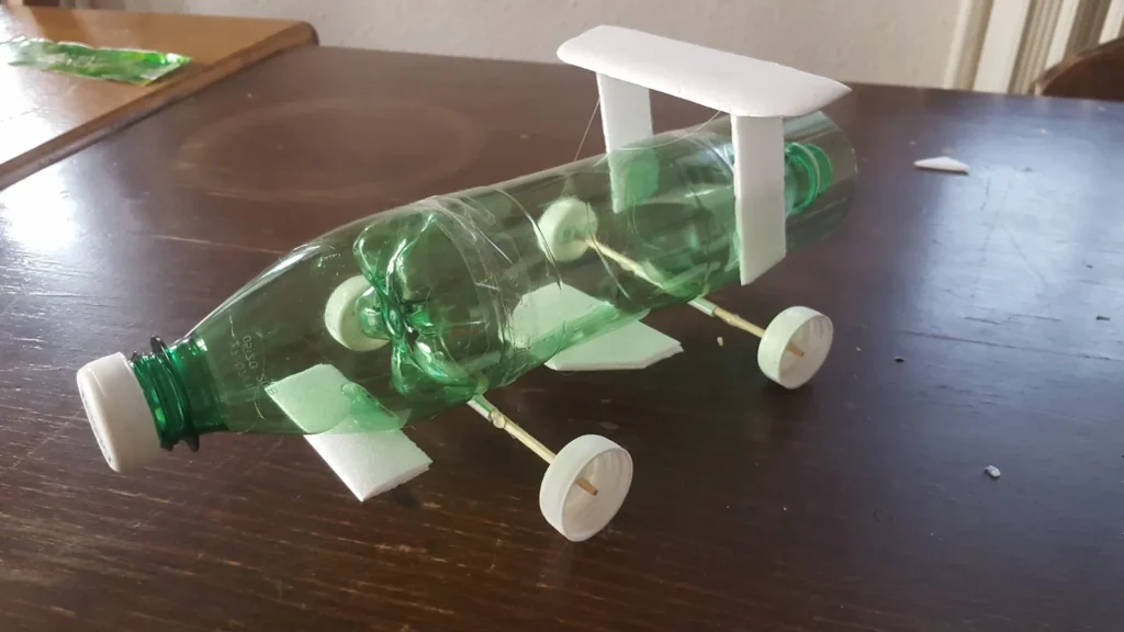 Dragster à eau réalisé à partir de bouteille et de bouchon par des enfants lors d'une activité créative.