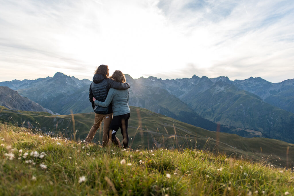 Photo prise en fin de journée en format paysage. Nous pouvons voir un couple dos à l'objectif en train d'observer les panoramas de La Toussuire.