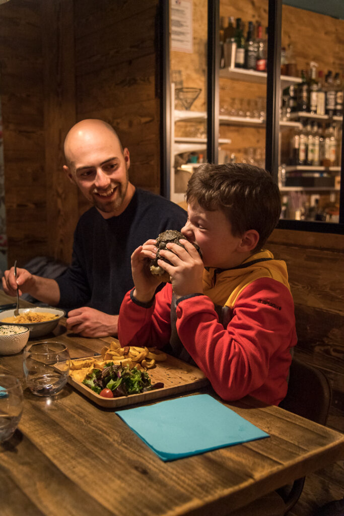 Photo prise en hiver en format portrait. Nous pouvons voir une famille en train de manger dans un restaurant.