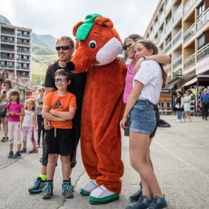 Animatie met de mascotte Toussy en een gezin in de hoofdstraat van La Toussuire