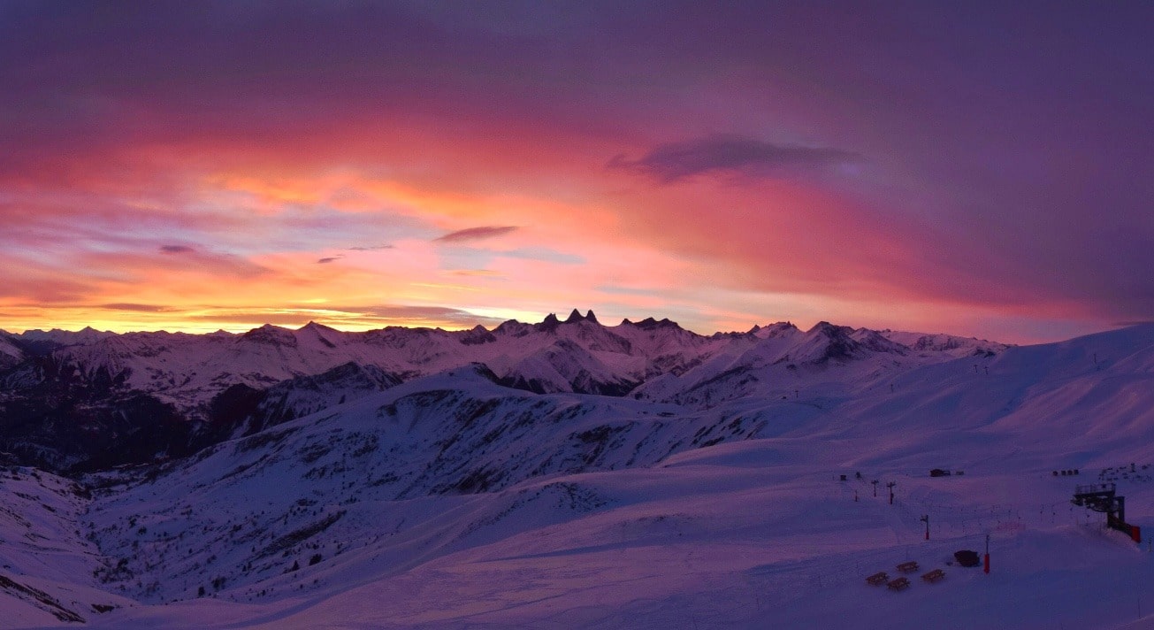 Photo prise en format paysage. Au moment du coucher de soleil sur les Aiguilles d'Arves en hiver. Le ciel est de couleur rose. 