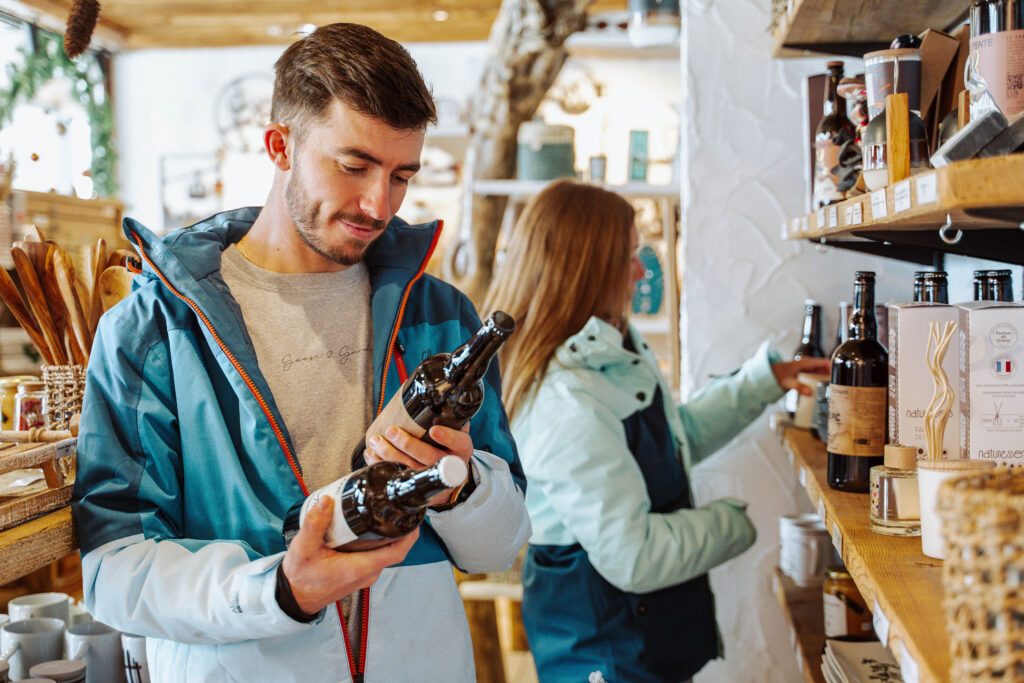 Photo prise de jour en hiver en format paysage. Nous pouvons voir un couple dans une boutique souvenir en train de regarder différents produits du magasin