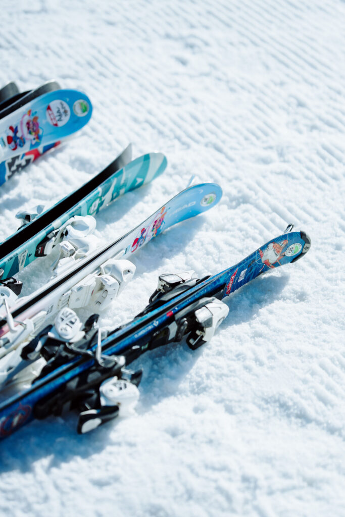 Photo en format portrait prise de jour en hiver. Nous pouvons voir des pairs de ski enfants poser dans la neige.