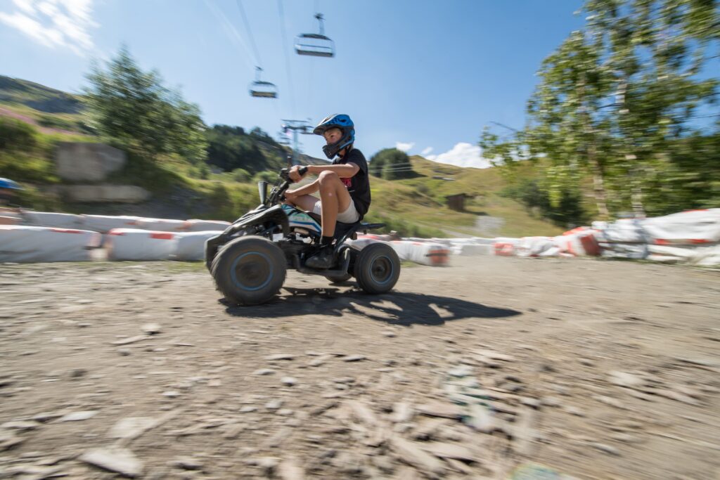 Photo pris de coté où nous voyons un enfant sur un quad électrique sur le parcours de Number One à la Toussuire