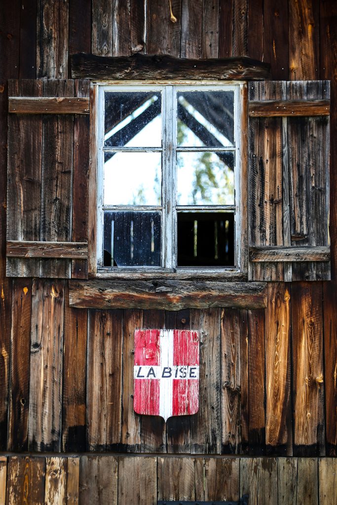 Zoom op een houten chalet van een bergbewoner. We kunnen een venster van de tijd perfect gecentreed zien op de afbeelding met een wapenschild van de vlag van Savoie eronder