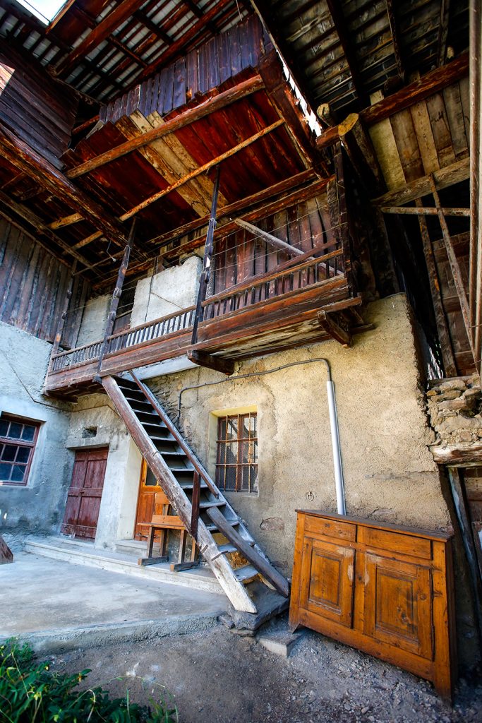 Typisch bouwwerk van een huis in Savoie. We kunnen een houten trap zien om naar de eerste etage van het huis te gaan/Het gelijkvloers is van beton en de eerste etage heeft een geraamte in hout