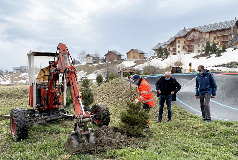 Photo prise en journée de printemps. nous pouvons voir des employés communaux avec le maire de la Toussuire ainsi qu'un élu en train de planter des sapins près de la Pumptrack