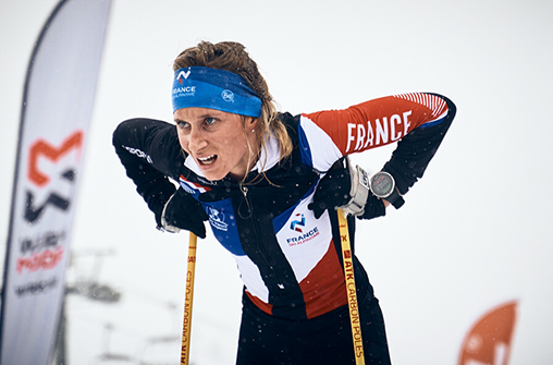 Portrait de Laura Deplanche lors d'une compétition de ski alpinisme. Nous voyons Laura debout mais épuisé après la course. Elle à la tenue de l'équipe de France.