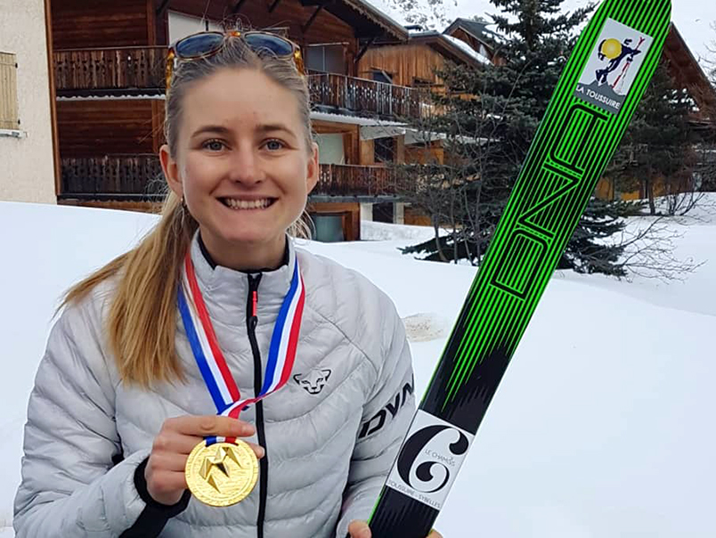 Portrait de Léna Bonnel à la Toussuire qui porte fièrement sa médaille d'or autour de son cou et ses skis dans sa main
