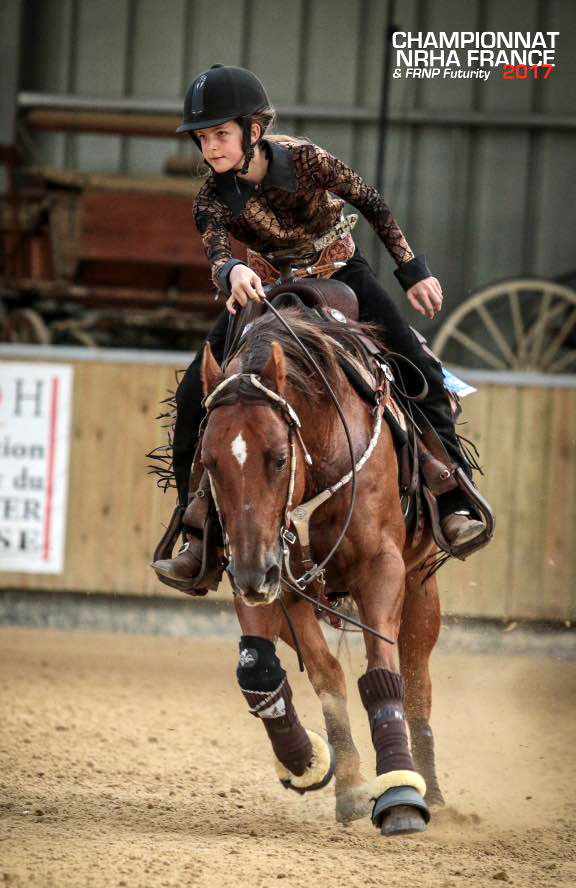 Portrait photo taken during 2017 French championships. Lou, facing the camera and wearing a Western outfit, is riding her horse and looking very focused.