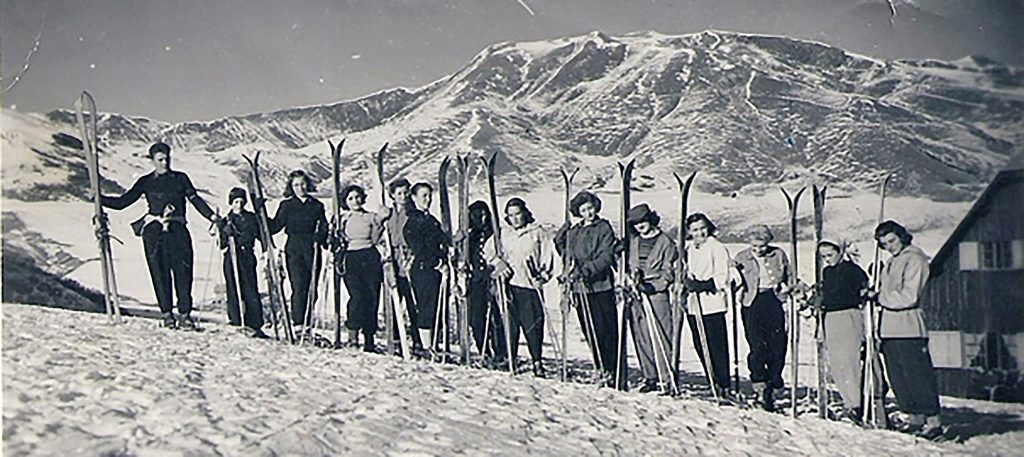 Photo ancienne en noir et blanc. Groupe de jeunes skieuses posant avec leur ski en ligne