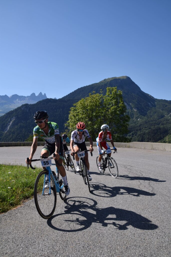 Quatre cyclistes dans un virage de la montée de la Toussuire en train de se disputer la victoire. En arrière plan nous pouvons observer les Aiguilles d'Arves et le Mont Charvin