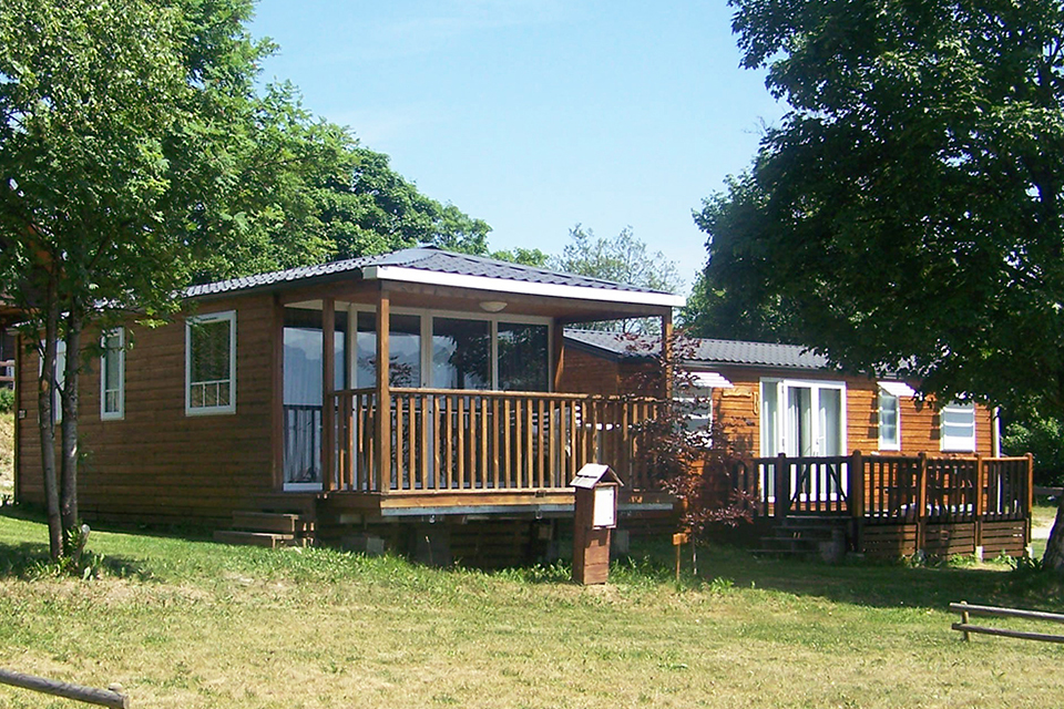 Photo prise en extérieur en été dans le camping de la Toussuire. Nous pouvons voir deux bungalows en bois entouré d'arbre