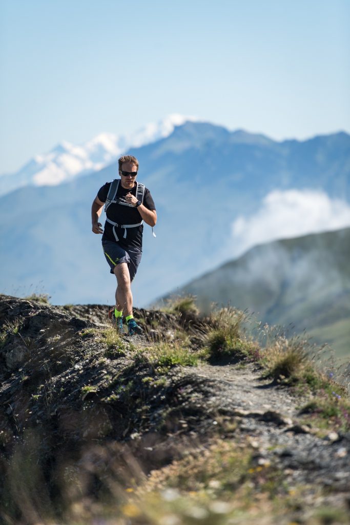 Traileur homme en action sur une crête de la Toussuire avec derrière lui le Mont-Blanc