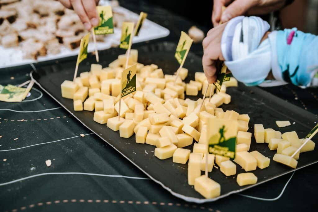 Cubes de fromage de Beaufort plantés de petits drapeaux avec logo Beaufort sur une assiette lors d'une animation gastronomique : le Rallye Gourmand