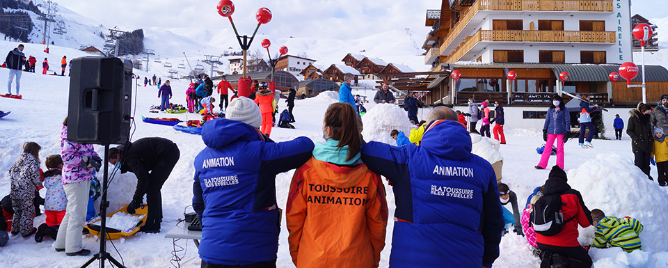 L'équipe d'animation de dos en hiver avec le flocage sur la veste. Ils sont face à des vacances en animations