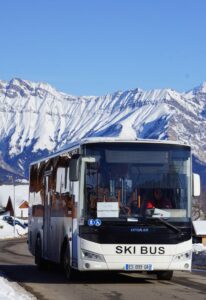 Interne pendel in de wintersportplaats La Toussuire op de ronde route met de besneeuwde bergen op de achtergrond. De pendels vervoeren gratis de toeristen in de wintersportplaats met bestemming de naburige wintersportplaats Corbier.