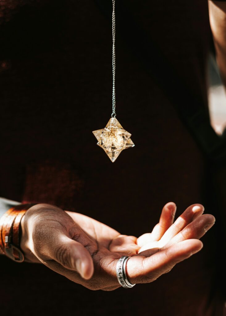 Mains tendues sous un pendentif étoile en cristal suspendu, symbolisant la détente et la sérénité pendant la Semaine Hygge – Bien‑être à La Toussuire.