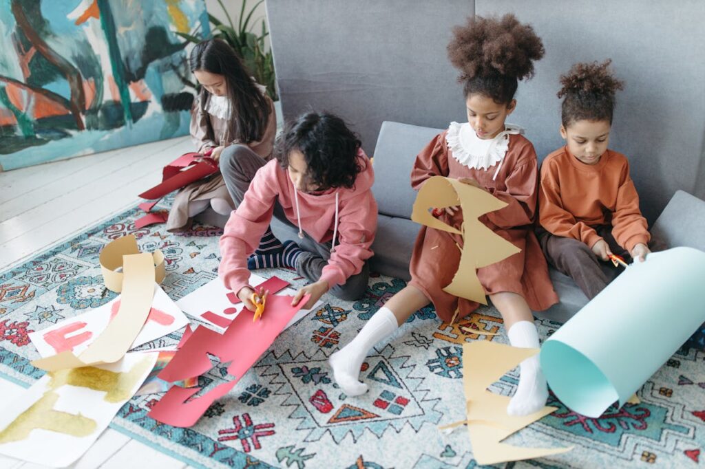 Enfants assis en train de découper du papier pour réaliser des déguisments